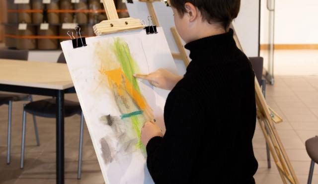 Young boy painting onto an easel.